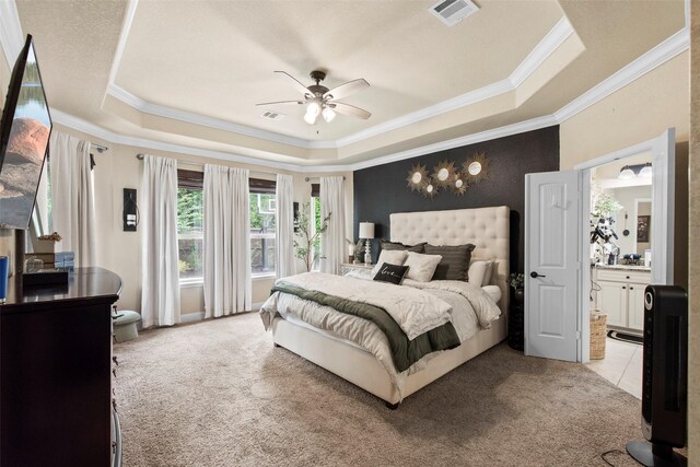 bedroom featuring crown molding, light colored carpet, a tray ceiling, and visible vents