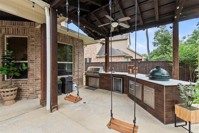 view of patio / terrace featuring grilling area, an outdoor kitchen, fence, and a ceiling fan