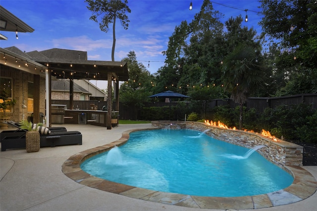 view of swimming pool with a patio, a fenced backyard, a fenced in pool, exterior kitchen, and an outdoor fire pit