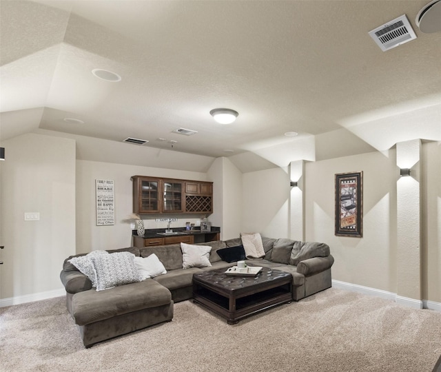 carpeted living area with visible vents, baseboards, and indoor wet bar