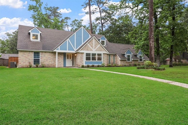 tudor-style house featuring a front lawn, cooling unit, and a shingled roof