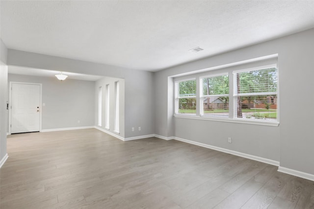 unfurnished room featuring baseboards, visible vents, and light wood-type flooring