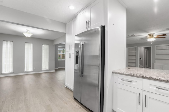 kitchen with a ceiling fan, light wood-style floors, stainless steel fridge with ice dispenser, white cabinets, and light stone countertops