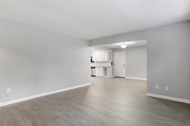 unfurnished living room with light wood-type flooring and baseboards