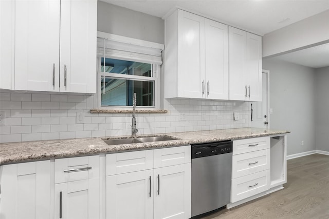 kitchen featuring stainless steel dishwasher, a sink, light wood-type flooring, white cabinetry, and decorative backsplash