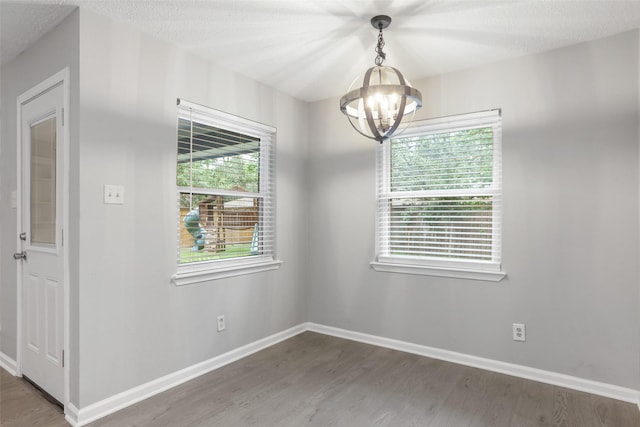 spare room with baseboards, a notable chandelier, and wood finished floors