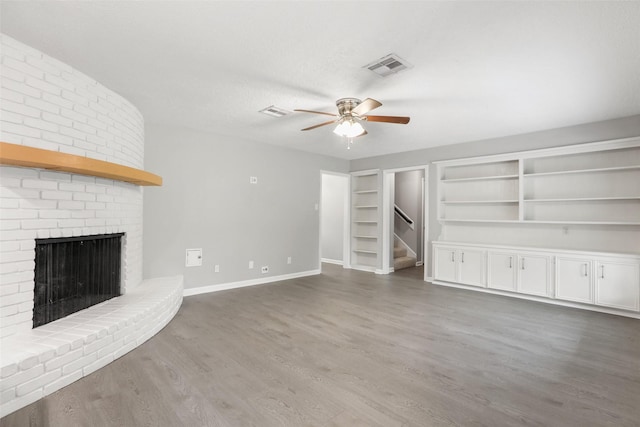 unfurnished living room with ceiling fan, baseboards, wood finished floors, and a fireplace