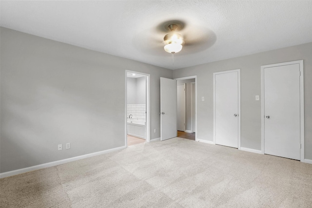 unfurnished bedroom with connected bathroom, baseboards, carpet flooring, and multiple closets