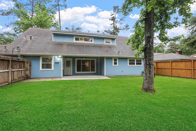 rear view of property featuring a patio area, a lawn, a shingled roof, and a fenced backyard