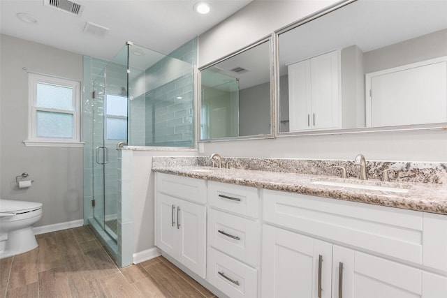 full bath with a sink, double vanity, a stall shower, toilet, and visible vents