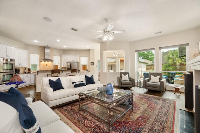 living room featuring dark wood finished floors, ceiling fan, visible vents, and recessed lighting