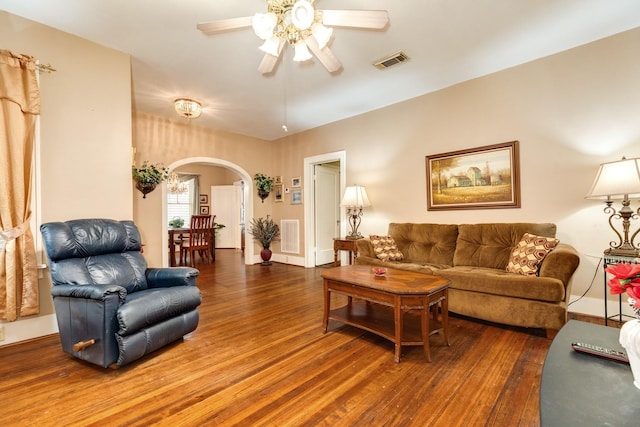 living room featuring arched walkways, baseboards, visible vents, a ceiling fan, and wood finished floors