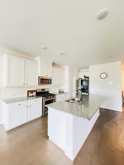 27915 Western Creek Ct, Katy, TX 77494 - kitchen with a sink, light stone countertops, a kitchen island with sink, appliances with stainless steel finishes, and white cabinetry