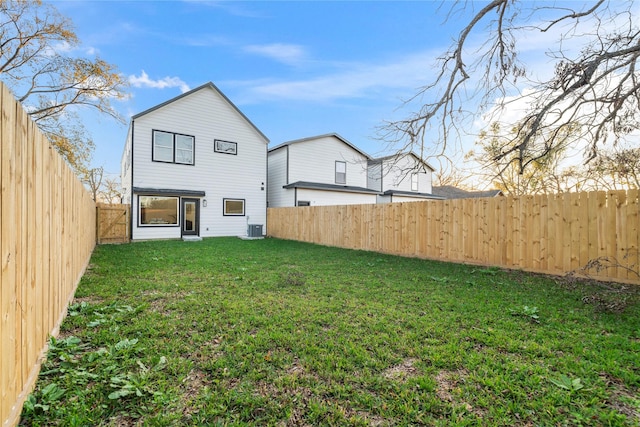 rear view of house with a lawn, cooling unit, and a fenced backyard