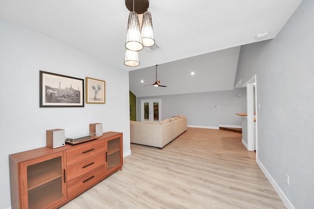 interior space with baseboards, a ceiling fan, light wood finished floors, and lofted ceiling