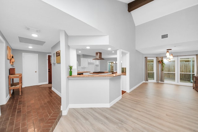 kitchen featuring baseboards, a peninsula, island exhaust hood, and visible vents