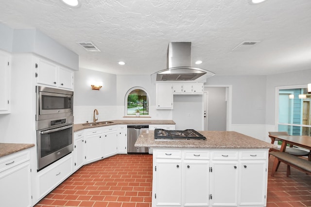 kitchen featuring island exhaust hood, visible vents, a sink, white cabinets, and stainless steel appliances