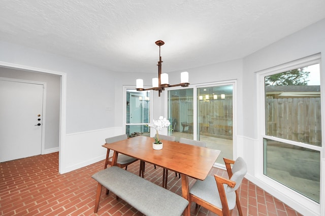 dining space with an inviting chandelier and brick patterned floor
