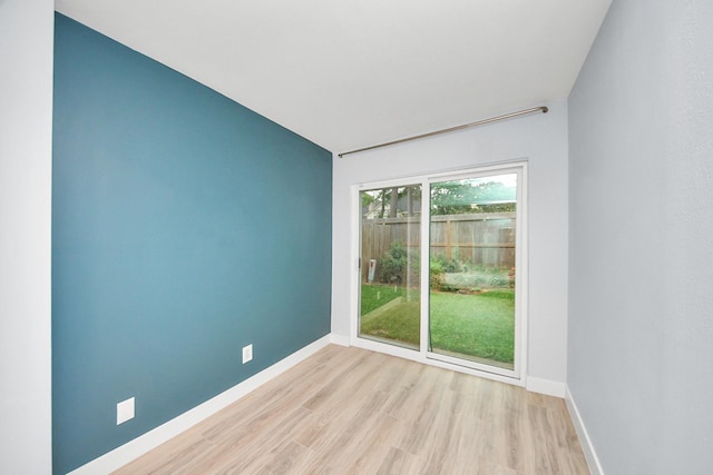 spare room with baseboards and wood finished floors