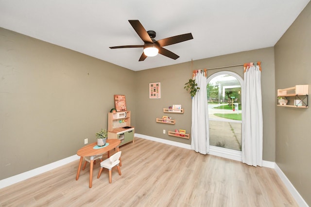 living area featuring baseboards, light wood-style flooring, and ceiling fan