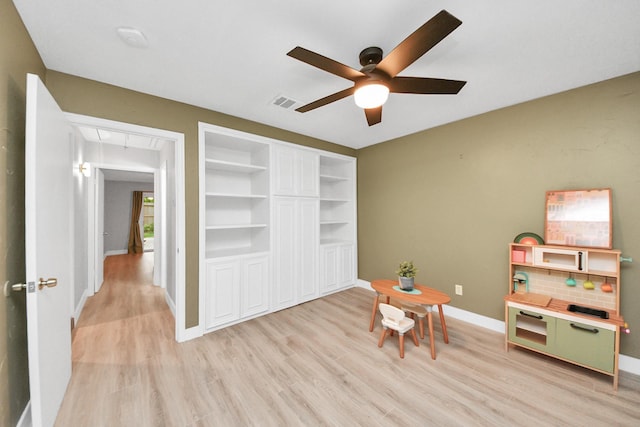recreation room featuring ceiling fan, baseboards, attic access, and light wood-type flooring