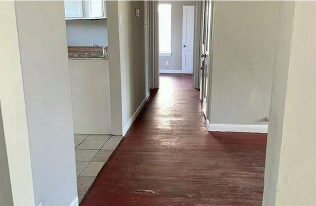 hall with baseboards, wood finished floors, and a sink