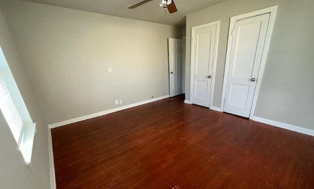 unfurnished bedroom with baseboards, a ceiling fan, and dark wood-style floors