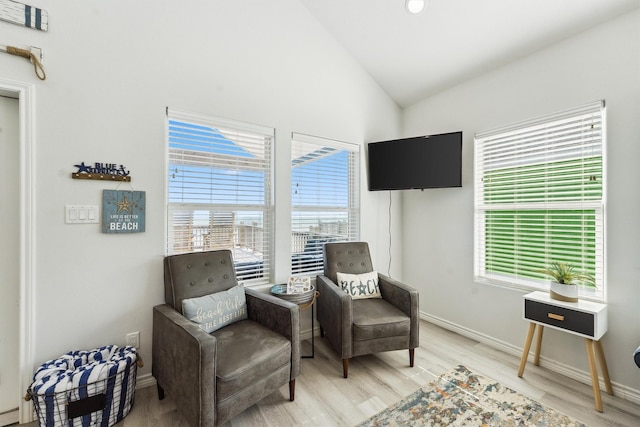 living area featuring vaulted ceiling, baseboards, and light wood-style flooring