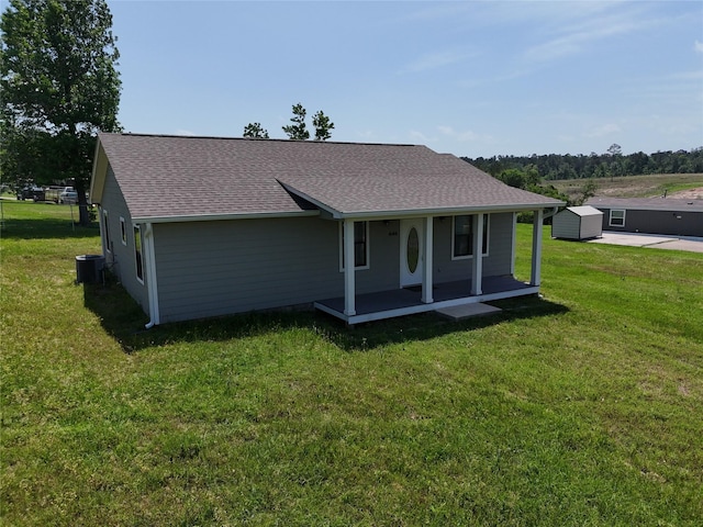 rear view of property featuring a porch, cooling unit, a yard, and a shingled roof