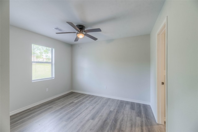 spare room featuring baseboards, wood finished floors, visible vents, and a ceiling fan
