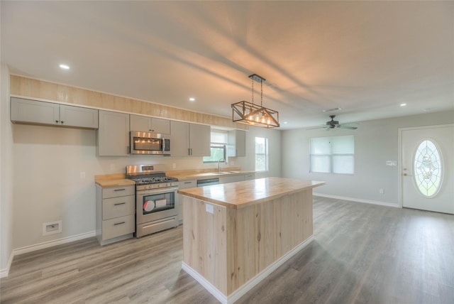 kitchen featuring stainless steel appliances, a sink, recessed lighting, butcher block countertops, and gray cabinets