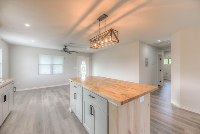 kitchen featuring baseboards, butcher block counters, light wood-type flooring, recessed lighting, and decorative light fixtures