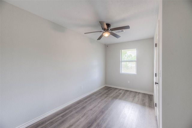 unfurnished room featuring wood finished floors, visible vents, a ceiling fan, and baseboards