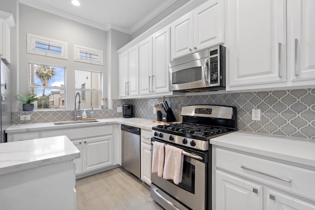 kitchen featuring crown molding, light stone countertops, white cabinetry, a sink, and appliances with stainless steel finishes