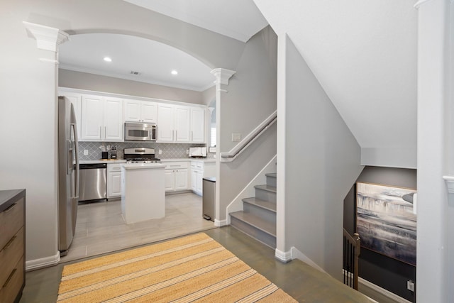 kitchen featuring a kitchen island, decorative columns, backsplash, white cabinets, and stainless steel appliances