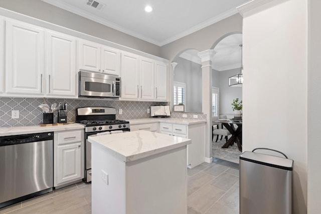 kitchen featuring appliances with stainless steel finishes, arched walkways, ornate columns, visible vents, and ornamental molding