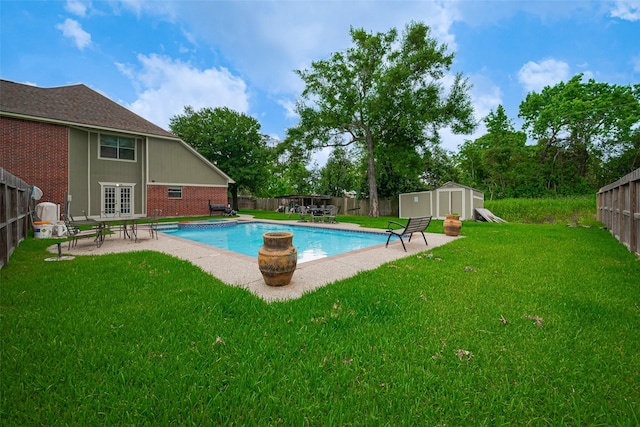 view of swimming pool featuring a shed, a fenced backyard, an outbuilding, a patio area, and a lawn