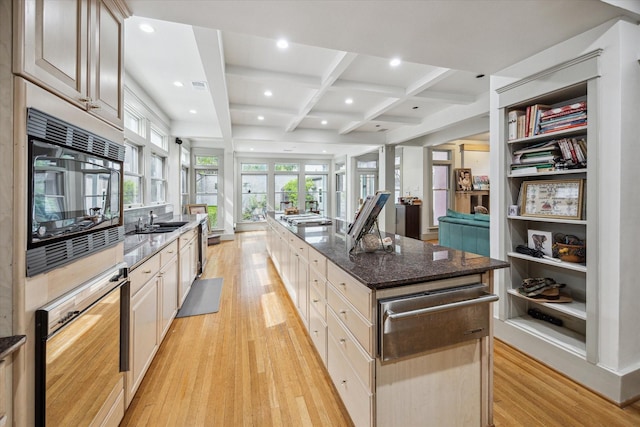 kitchen with coffered ceiling, black microwave, a sink, and light wood-style flooring