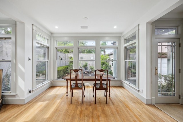sunroom with wood finished floors, visible vents, and plenty of natural light