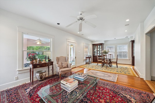 living room with baseboards, wood finished floors, a ceiling fan, and plenty of natural light