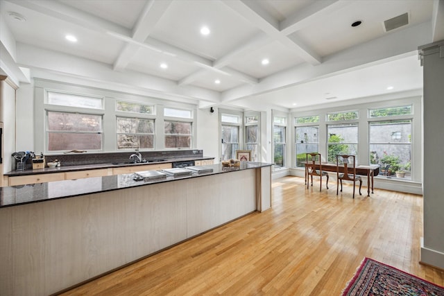 kitchen with a sink, beam ceiling, light wood-type flooring, coffered ceiling, and visible vents