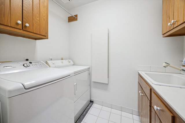 laundry room featuring a sink, light tile patterned floors, cabinet space, and independent washer and dryer