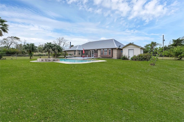 rear view of house featuring fence, an outdoor pool, and a lawn