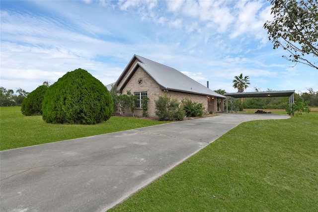 view of front of home with brick siding, a detached carport, driveway, and a front lawn