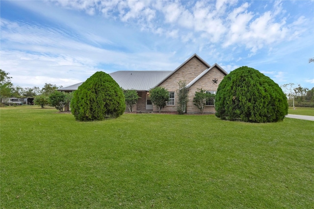 view of front of house with brick siding, a front lawn, and metal roof