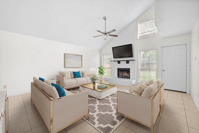 living room with light tile patterned flooring, plenty of natural light, a ceiling fan, a brick fireplace, and high vaulted ceiling