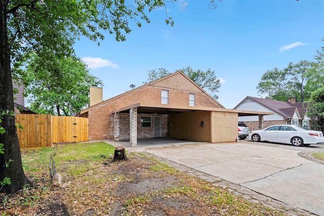 view of front of property featuring a gate, a chimney, fence, an attached carport, and brick siding