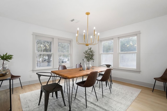 dining area with a wealth of natural light, a notable chandelier, and light wood finished floors