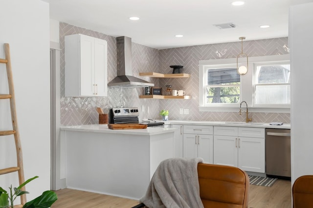 kitchen featuring wall chimney exhaust hood, stainless steel appliances, a sink, visible vents, and light countertops