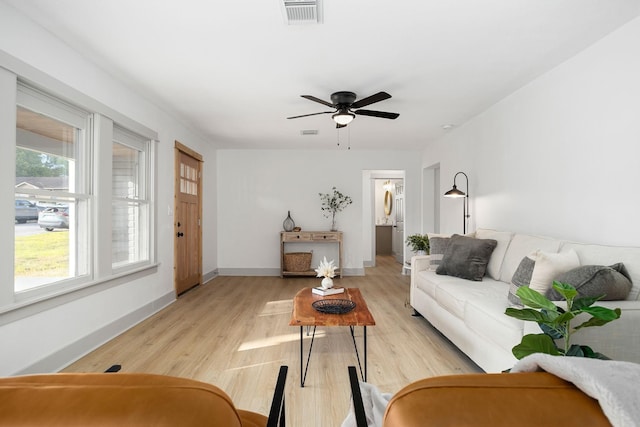 living area featuring baseboards, light wood-style flooring, visible vents, and ceiling fan